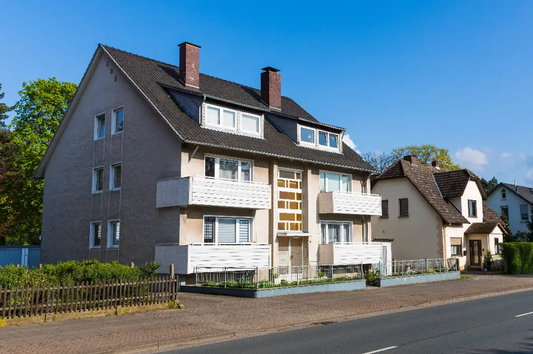 Älteres Mehrfamilienhaus mit Balkonen an einer Durchgangsstraße — ein typisches Ankaufsobjekt von Papakaufthaus.de