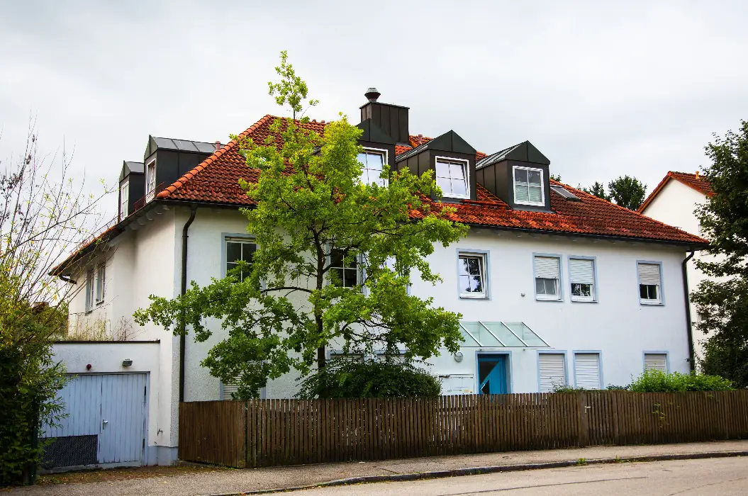 Ruhiges Mehrfamilienhaus mit Garten und Gartenzaun in einer Wohnstraße — häufig der Typ Haus, der aus einem Nachlass verkauft wird